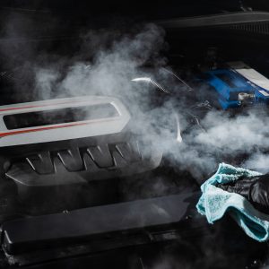 Process of steam cleaning car engine from dust and dirt. Steaming washing of motor of auto in detailing auto service